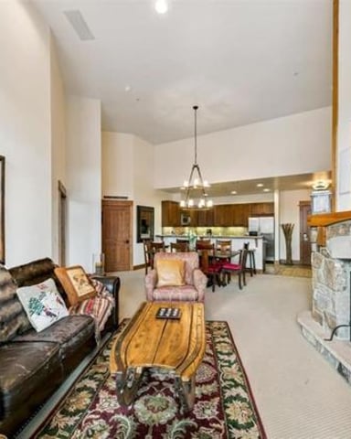 Open-plan living room with leather sofa, fireplace, and view into kitchen and dining area