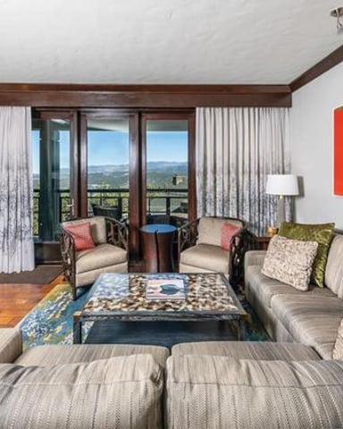 Spacious living room with sectional sofa, fireplace, and panoramic mountain views through glass doors