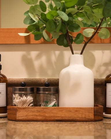 Bathroom counter with hand soap and lotion bottles, white vase with eucalyptus branches, and wooden accessories
